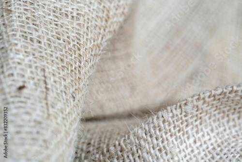 This is a close-up image of burlap fabric showcasing its coarse texture and woven pattern with focus on the overlapping layers. photo