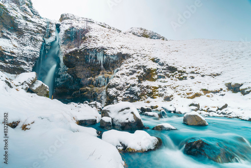 Snowy waterfall with vibrant blue river photo