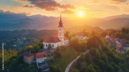 Aerial Panoramic View of Sveti Tomaz Church in Skofja Loka, Slovenia, with Golden Sunset and Julian Alps in Summer - Scenic Landscape photo