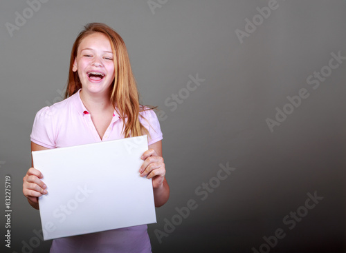 A girl is holding a white sign and smiling
