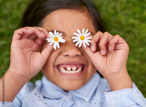 Girl, child and flower on eyes with happy on grass for playful fun, nature and calm vacation with enjoy freedom. Smile, kid and relax, care and plant for glasses, field and sustainable in summer