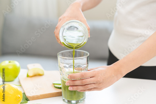 Detox juice concept, Hand of woman, girl holding bottle making green vegetable smoothie pouring in glass for diet at home kitchen, drinking healthy meal food for weight loss. Lifestyle vegan nutrition