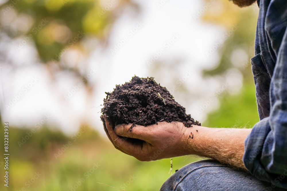 Holding soil in a hand, feeling compost in a field in Tasmania Australia.