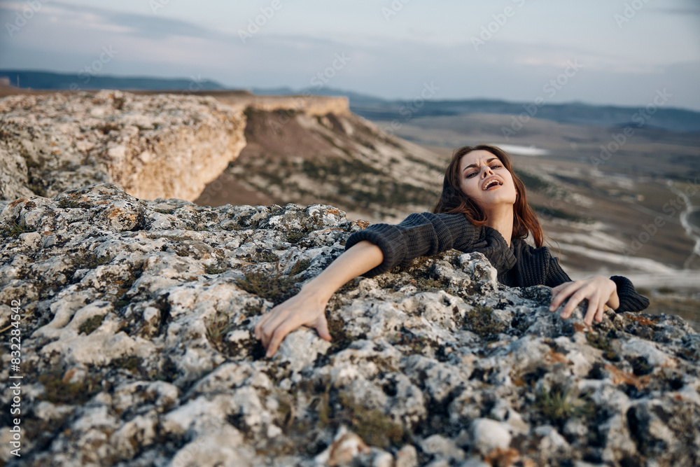 Serene woman laying on top of rock with arms outstretched and eyes closed in peaceful tranquility