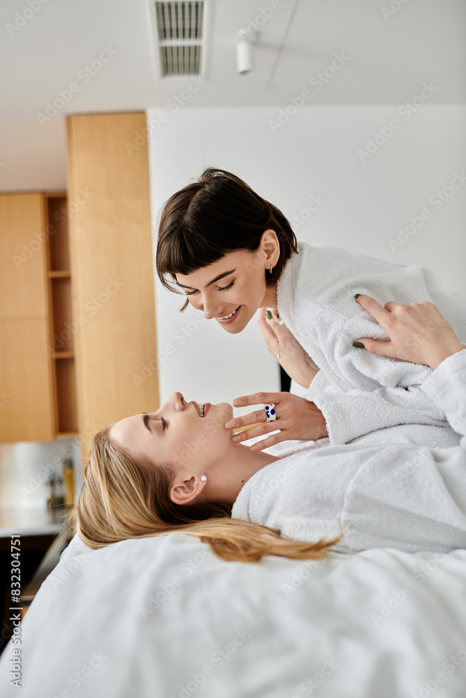 A beautiful lesbian couple in bath robes, peacefully laying next to each other in a cozy hotel room. A beautiful lesbian couple in bath robes, peacefully laying next to each other in a cozy hotel room.