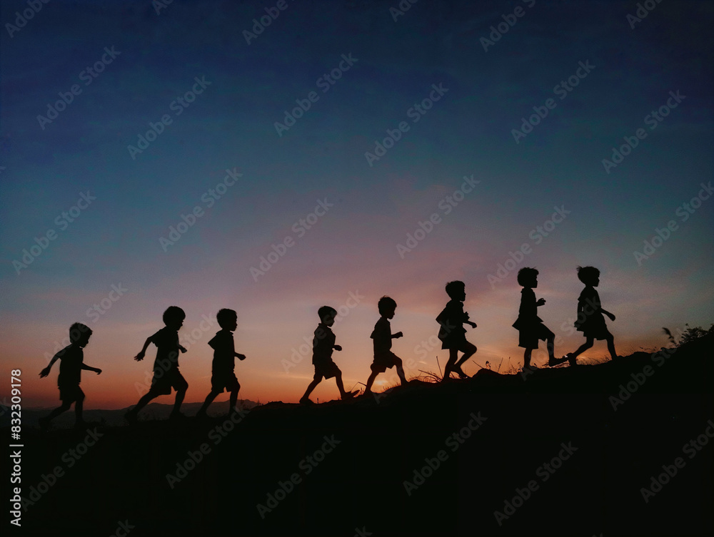 Silhouette of a group of children walking up a hill at dusk time. Silhouette of a group of children walking up a hill at dusk time.