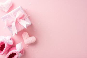 Pink baby shower decorations featuring knitted baby booties, heart shapes, and a gift box with ribbon on a pink background