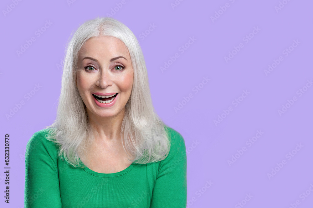 An elderly woman with joyful emotions on her face shows her delight and joy on a lilac background An elderly woman with joyful emotions on her face shows her delight and joy on a lilac background