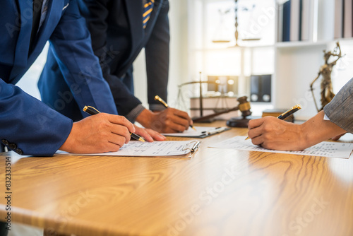 A team meeting of business people and a lawyer in formal suits is taking place at a desk, discussing a contract and various aspects of the law and litigation. photo