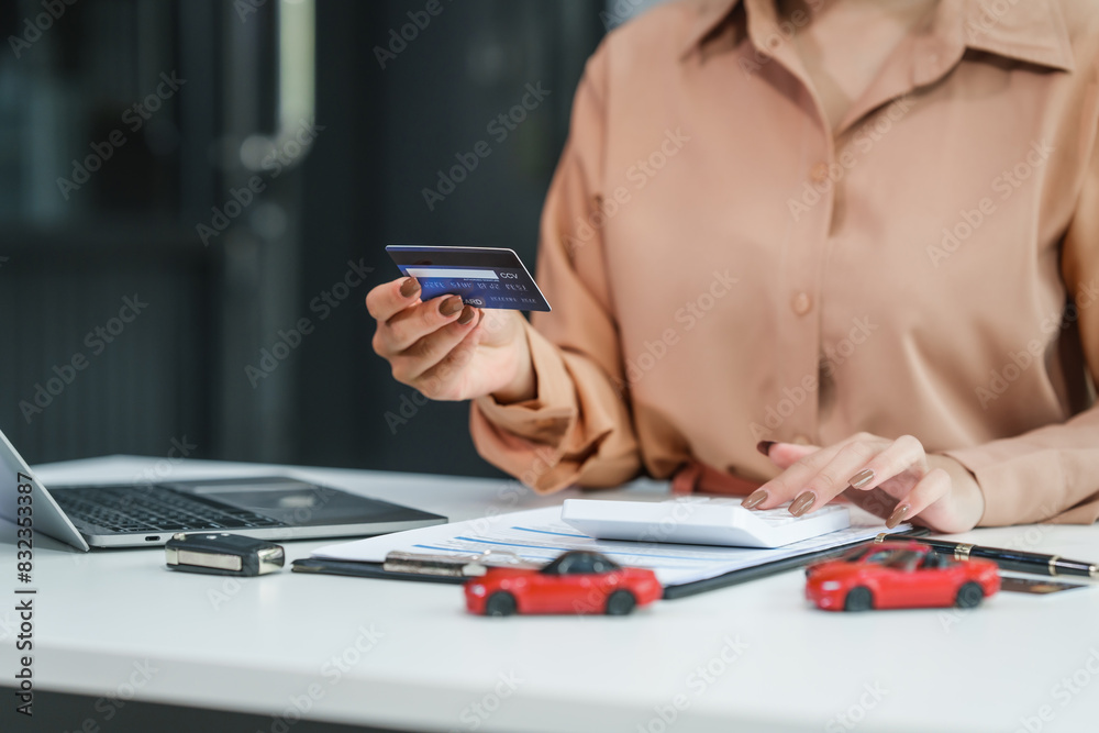 Fototapeta premium Asian businesswoman negotiates the sale of a car, discussing insurance and financing options, used car loans, premiums, deductibles, and various coverage types to ensure comprehensive protection.