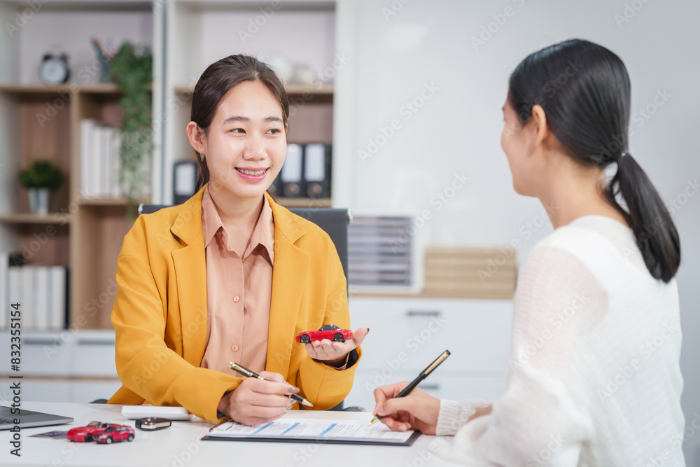 Asian businesswoman and a salesman discuss car sales, insurance, and financing with a customer at a desk, covering used car loans, premiums, deductibles, and various insurance coverage options. Asian businesswoman and a salesman discuss car sales, insurance, and financing with a customer at a desk, covering used car loans, premiums, deductibles, and various insurance coverage options.
