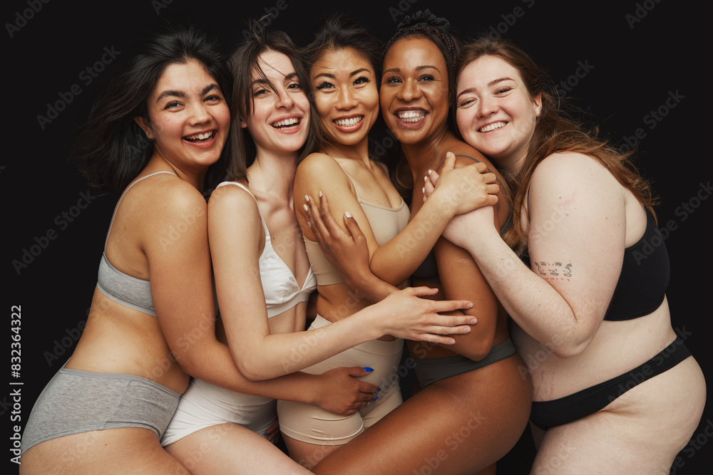 Diverse group of five women dressed in underwear embrace each other and smiling warmly against black studio background. Concept of beauty and fashion, support, unity, wellness, body positivity. Diverse group of five women dressed in underwear embrace each other and smiling warmly against black studio background. Concept of beauty and fashion, support, unity, wellness, body positivity.
