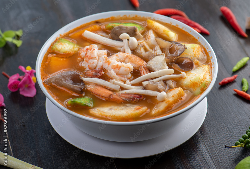 A bowl of Tom Yum soup with shrimp, mushrooms, and vegetables. A bowl of Tom Yum soup with shrimp, mushrooms, and vegetables.