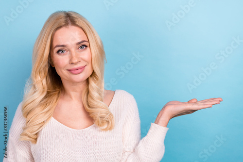 Photo of charming cute adorable woman wear stylish white clothes hold empty space isolated on blue color background