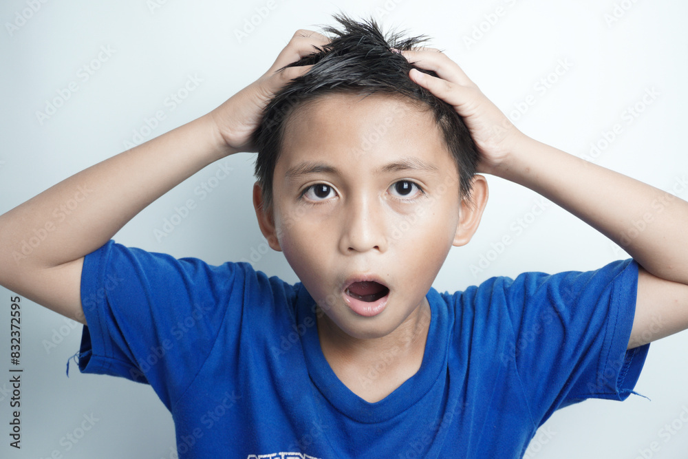Portrait of little boy holding hands on head, screaming with opened mouth and crazy expression. Surprised or shocked face Portrait of little boy holding hands on head, screaming with opened mouth and crazy expression. Surprised or shocked face