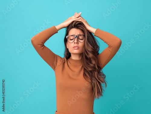 Woman suffering from stress or a headache grimacing in pain, she holds her hand to her temple