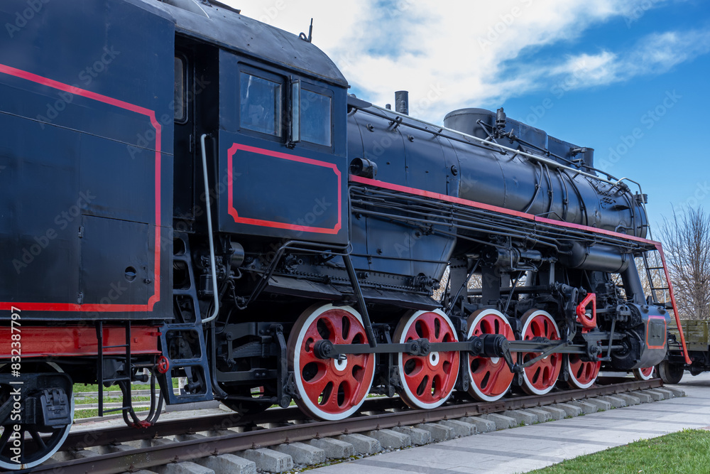A large steam locomotive at the railway station.  Mainline passenger steam locomotive. Ancient railway transport. Transportation of goods by rail in the last century.