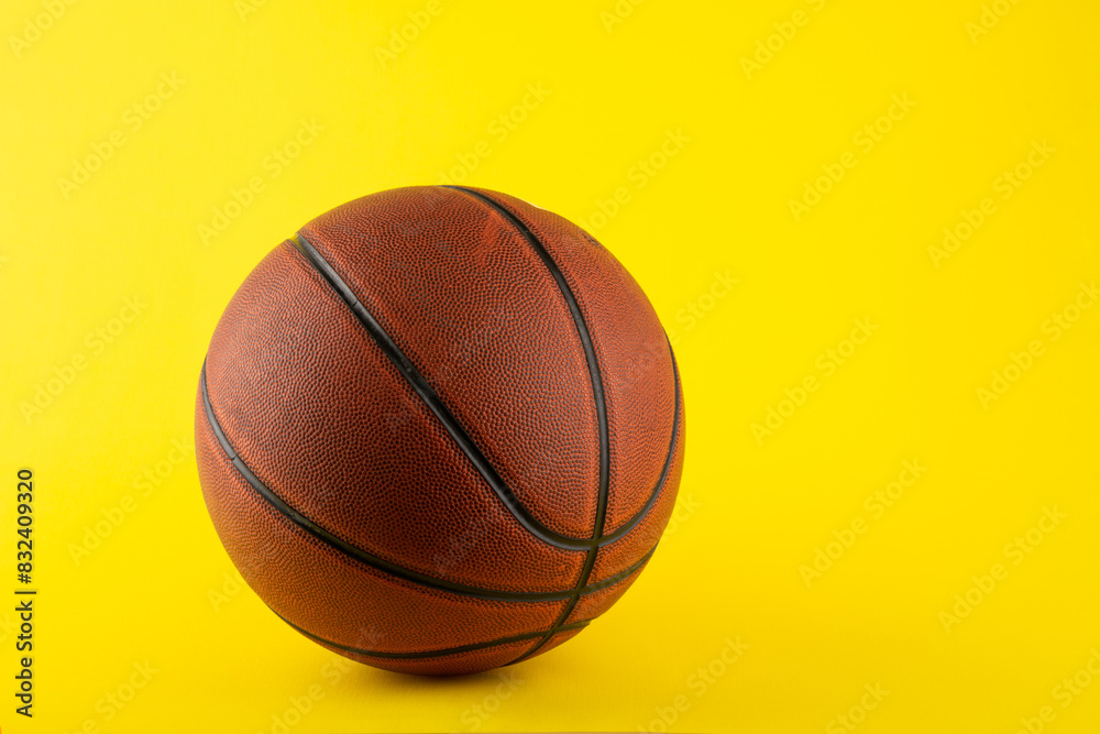 Basketball ball on yellow background with copy space