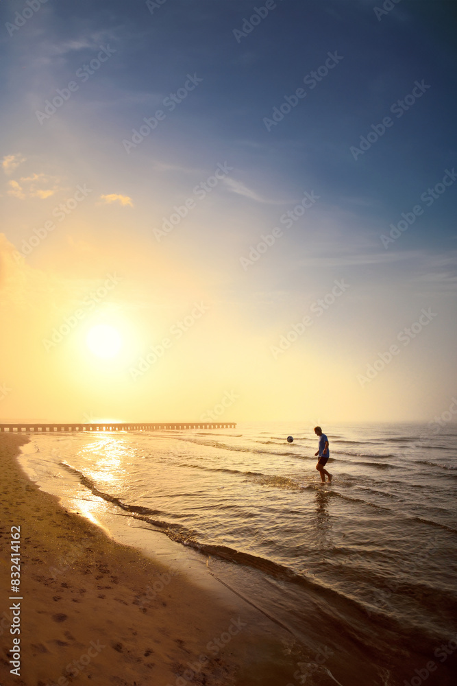Young man playing football with soccer ball at summer beach in the calm fogy morning. Vertical photo in smartphone background format. Edit space Young man playing football with soccer ball at summer beach in the calm fogy morning. Vertical photo in smartphone background format. Edit space