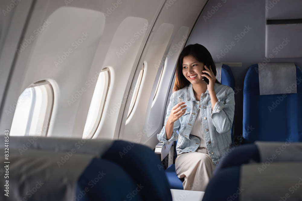 Young woman talking on smartphone during flight on airplane. Concept of travel and communication