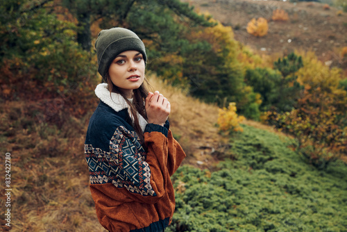 A stylish woman enjoying the autumn beauty of the forest on a hill during a peaceful nature trip