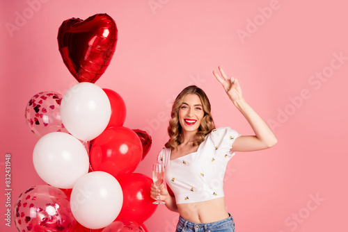 Photo portrait of lovely young woman balloons hold champagne v-sign dressed stylish white garment hairdo isolated on pink color background