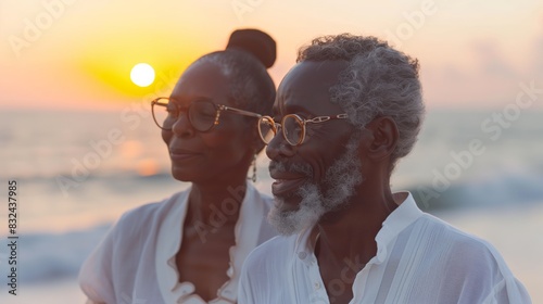 Portrait of a happy senior African American couple wearing eyeglasses standing at the beach and looking away