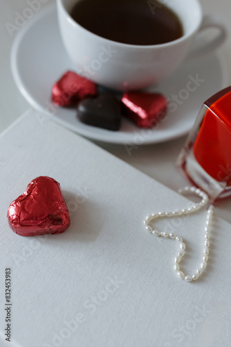 Valentine's Day. heart-shaped candies and a cup of tea. red perfume and a white book