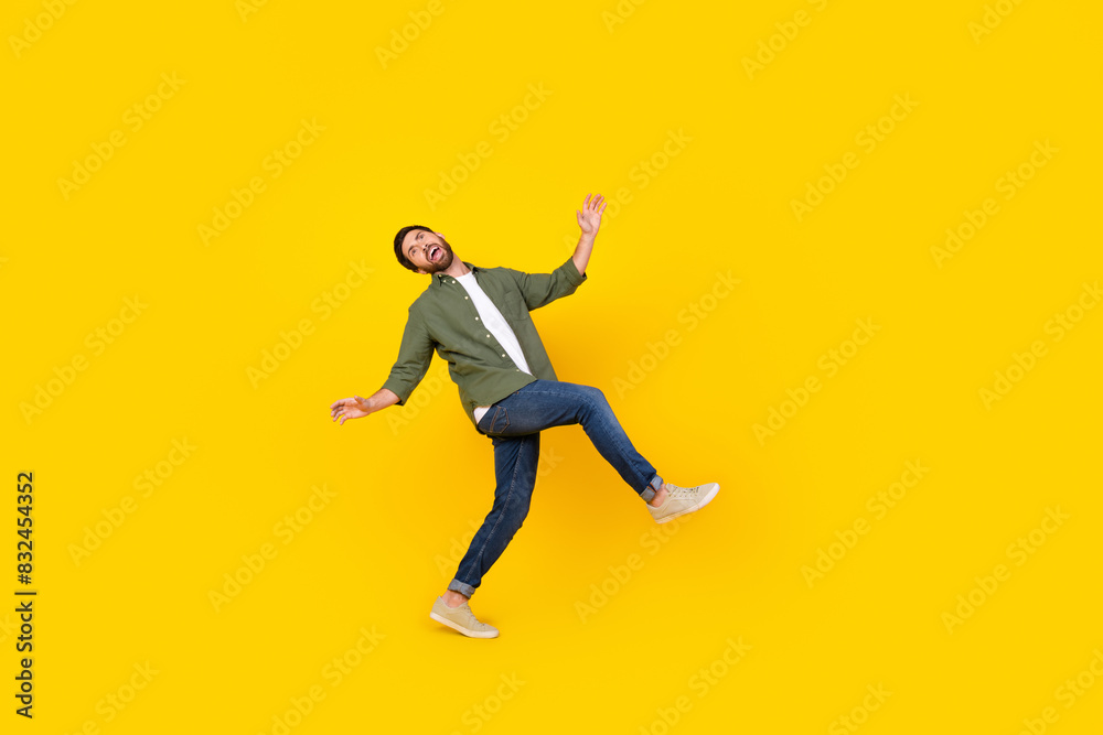 Full size photo of nice young man dance walk empty space wear shirt isolated on yellow color background