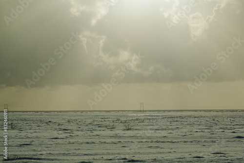 Overcast sky over snowy plain with power lines