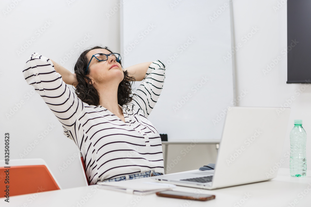 Woman Relaxing at Her Office Desk With Laptop in the Afternoon Woman Relaxing at Her Office Desk With Laptop in the Afternoon