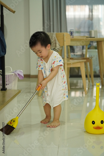 Asian young boy in white clothes sweeping with fantacy yellow broom set and home vibe background