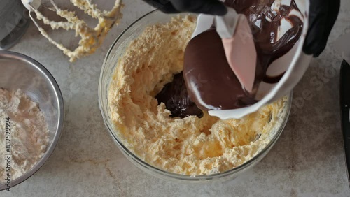 Adding the melted chocolate to the bowl with the cream. The process of making a chocolate cake
