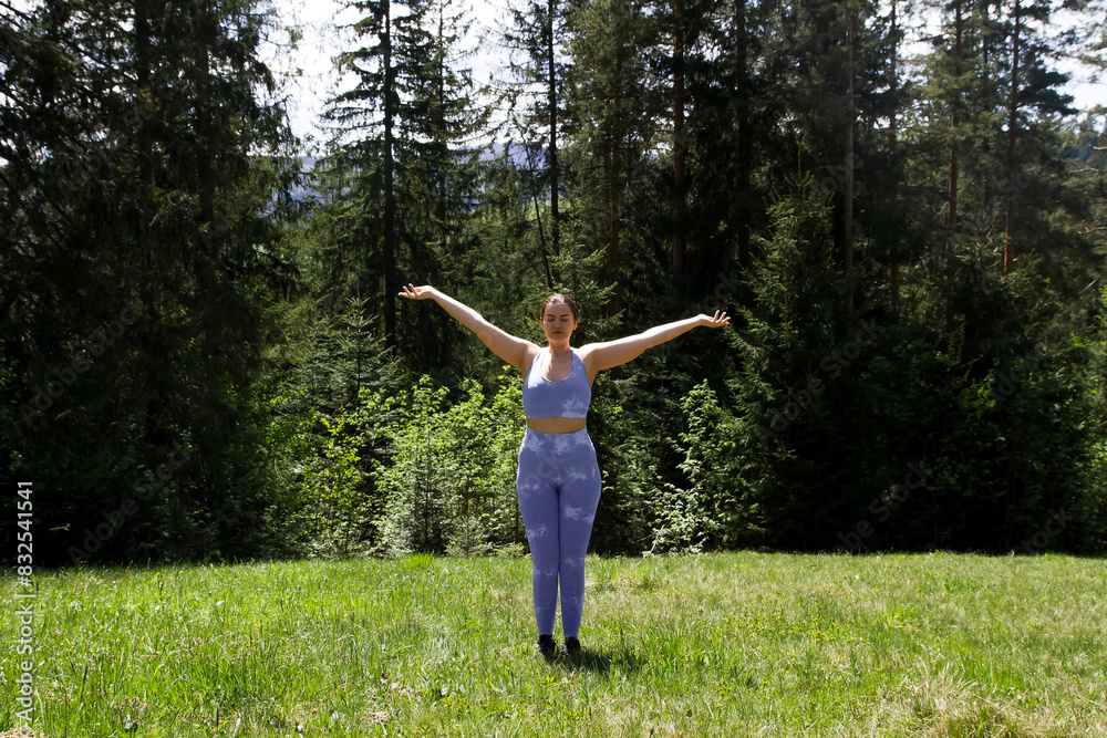 woman doing physical exercises, sports, yoga, in a blue tight-fitting suit in the fresh air