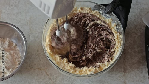 Mixing melted chocolate with butter cream with an electric mixer. The process of making a chocolate cake