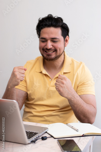 Student making celebration gesture front his laptop in virtual class