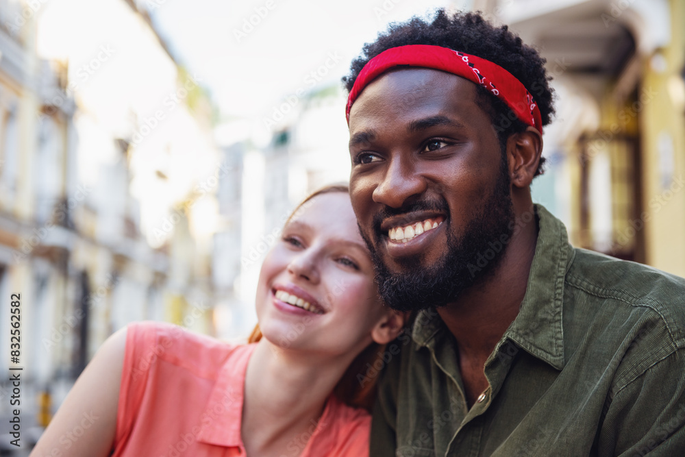 Young cheerful couple where a man and a blonde woman are smiling embracing while walking down a city street Young cheerful couple where a man and a blonde woman are smiling embracing while walking down a city street