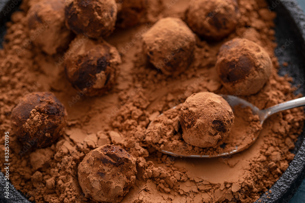 Fototapeta premium Artisanal chocolate truffles dusted with cocoa powder on a plate with a spoon