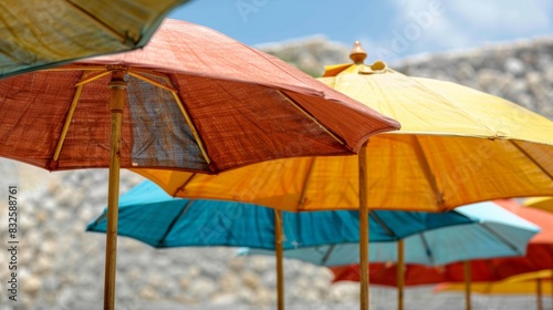 A line of colorful handmade beach umbrellas with wooden poles and organic cotton fabric providing shade while being kind to the environment.