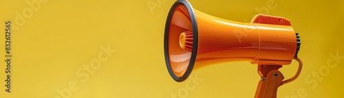 Closeup of an orange megaphone in action, a symbol of activism and announcement, against a minimalist yellow background photo