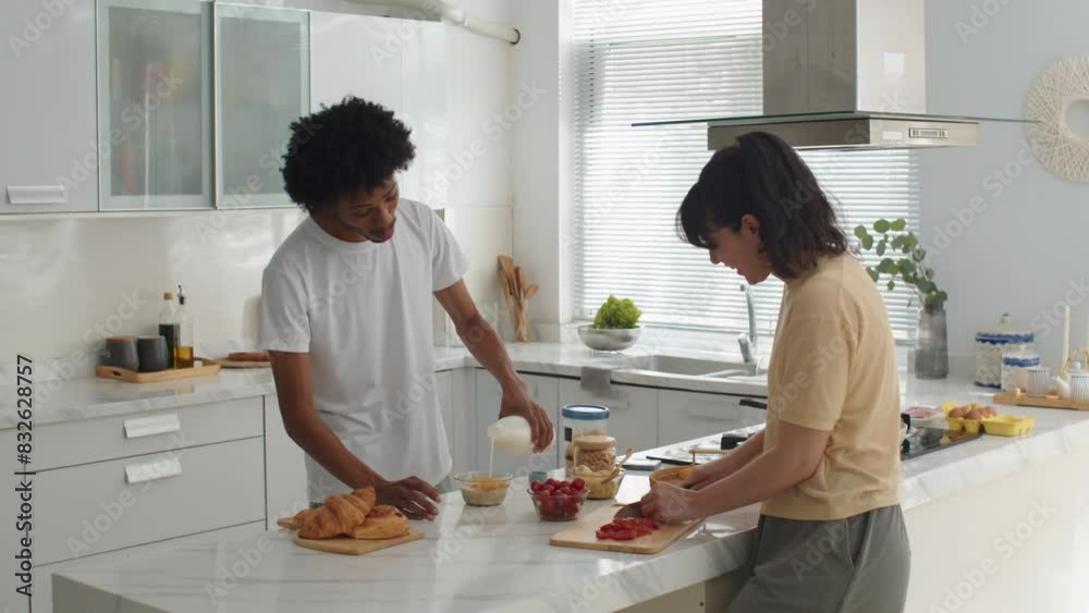 Biracial happy spouses chatting when cooking healthy breakfast at kitchen of their flat
