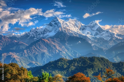 A breathtaking view of snow-capped mountains rising above lush green hills under a bright blue sky.