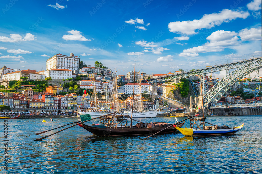 Obraz premium View of Porto city and Douro river with traditional boats with port wine barrels and sailing ship from famous tourist viewpoint Marginal de Gaia riverfront. Porto, Vila Nova de Gaia, Portugal