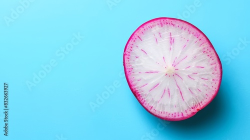  A detailed shot of a halved fruit against a blue backdrop, revealing its pink interior