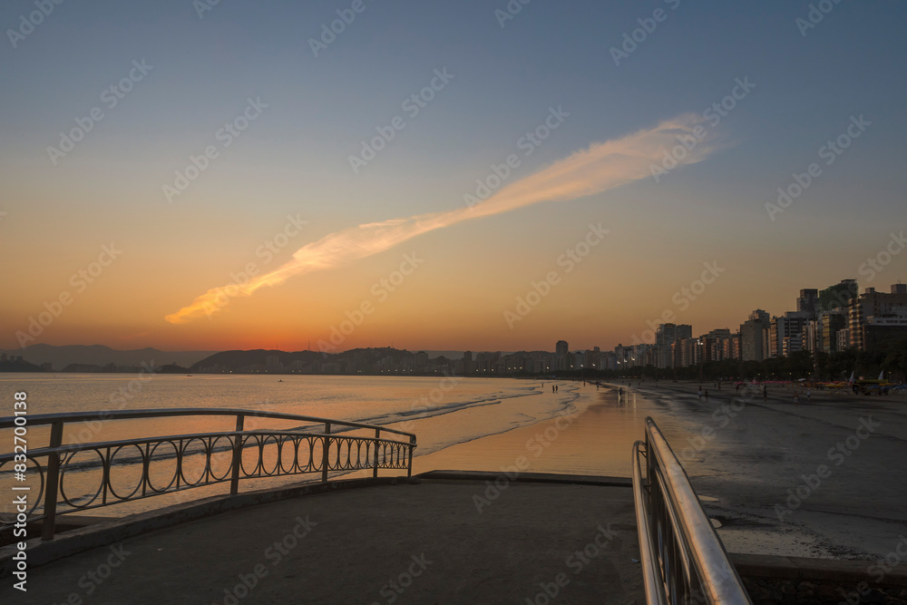 Bridge over water channel nº6 during sunset at the beach. In the background, the strip of sand and the buildings on the coast of the city of Santos, Brazil.