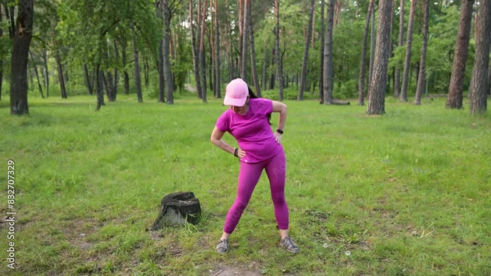 Mature woman in a pink fitness outfit performing exercises in a green park, enjoying outdoor training. High quality FullHD footage Mature woman in a pink fitness outfit performing exercises in a green park, enjoying outdoor training. High quality FullHD footage