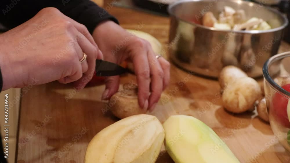 A woman slices vegetables for grilling on a wooden board, close-up side view A woman slices vegetables for grilling on a wooden board, close-up side view