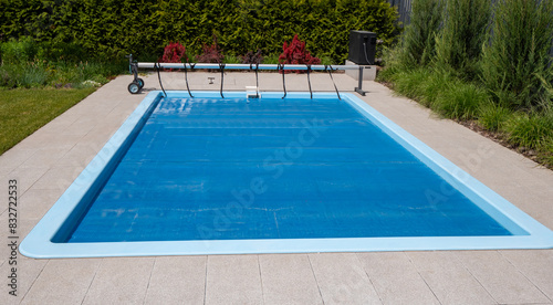 Home outdoor pool covered with film to save chemicals, water and heat preservation