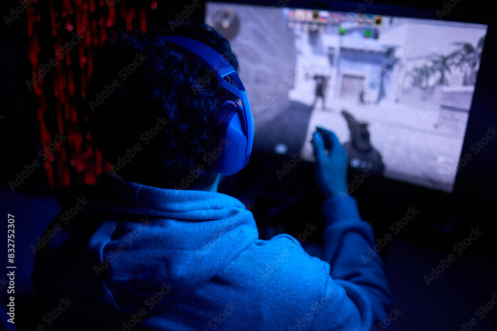 A coder is working late at night on a computer screen, coding and using a smartphone app