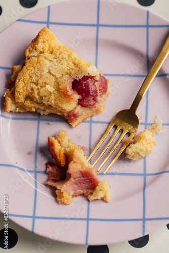 eating a slice of cherry clafoutis on purple plate with grid pattern